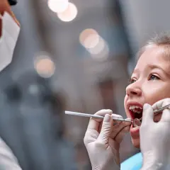 Mała dziewczynka u dentysty. Czas na kontrolę, kiedy wypadają piątki u dzieci, to ważny moment.