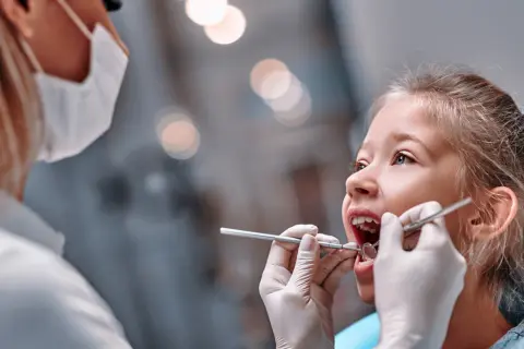 Mała dziewczynka u dentysty. Czas na kontrolę, kiedy wypadają piątki u dzieci, to ważny moment.