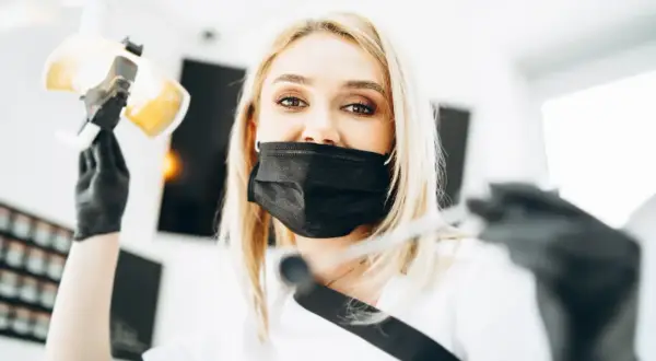 Dentystka w masce przygotowuje się do lakierowania zębów. To zabieg ochronny dla szkliwa.