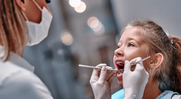 Mała dziewczynka u dentysty. Czas na kontrolę, kiedy wypadają piątki u dzieci, to ważny moment.