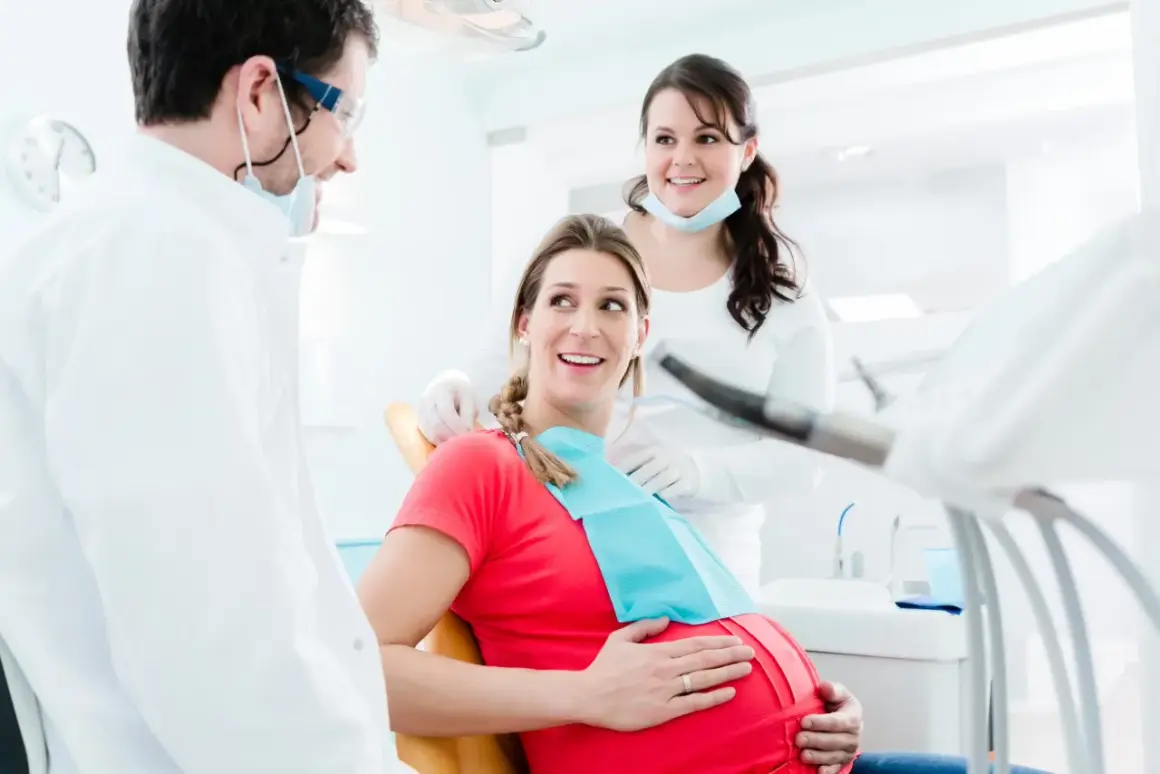 Uśmiechnięta ciężarna pacjentka u dentysty. Dba o zdrowie zębów, by uniknąć próchnicy w ciąży.