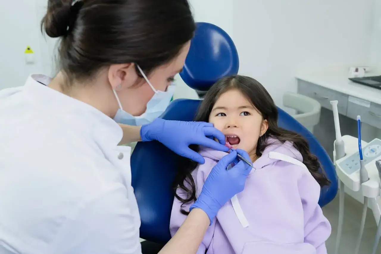 Dentystka bada zęby dziewczynki, która zastanawia się, czy zęby 5 wypadają.
