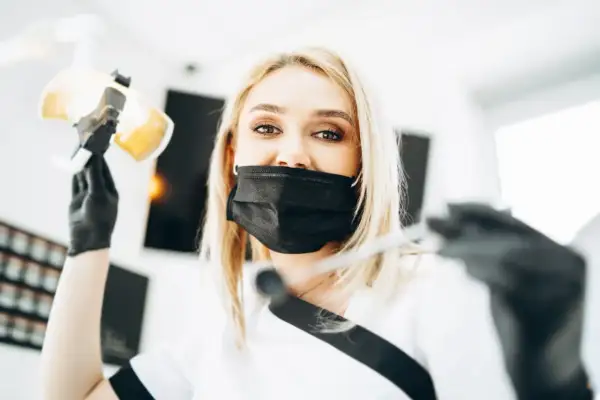 Dentystka w masce przygotowuje się do lakierowania zębów. To zabieg ochronny dla szkliwa.