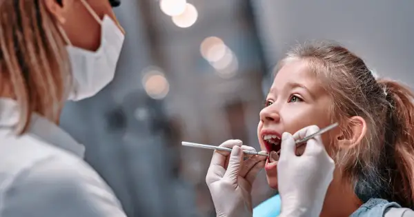Mała dziewczynka u dentysty. Czas na kontrolę, kiedy wypadają piątki u dzieci, to ważny moment.